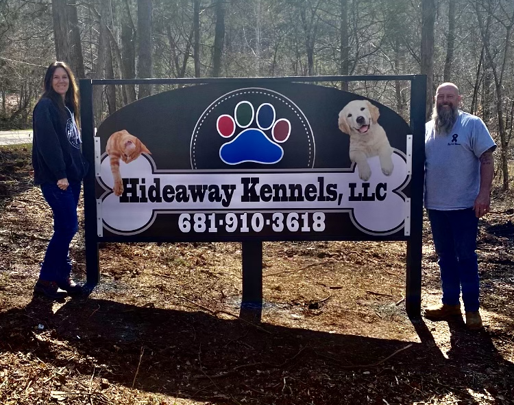 Owners Paul and Charlene Rippetoe standing beside the Hideaway Kennels sign